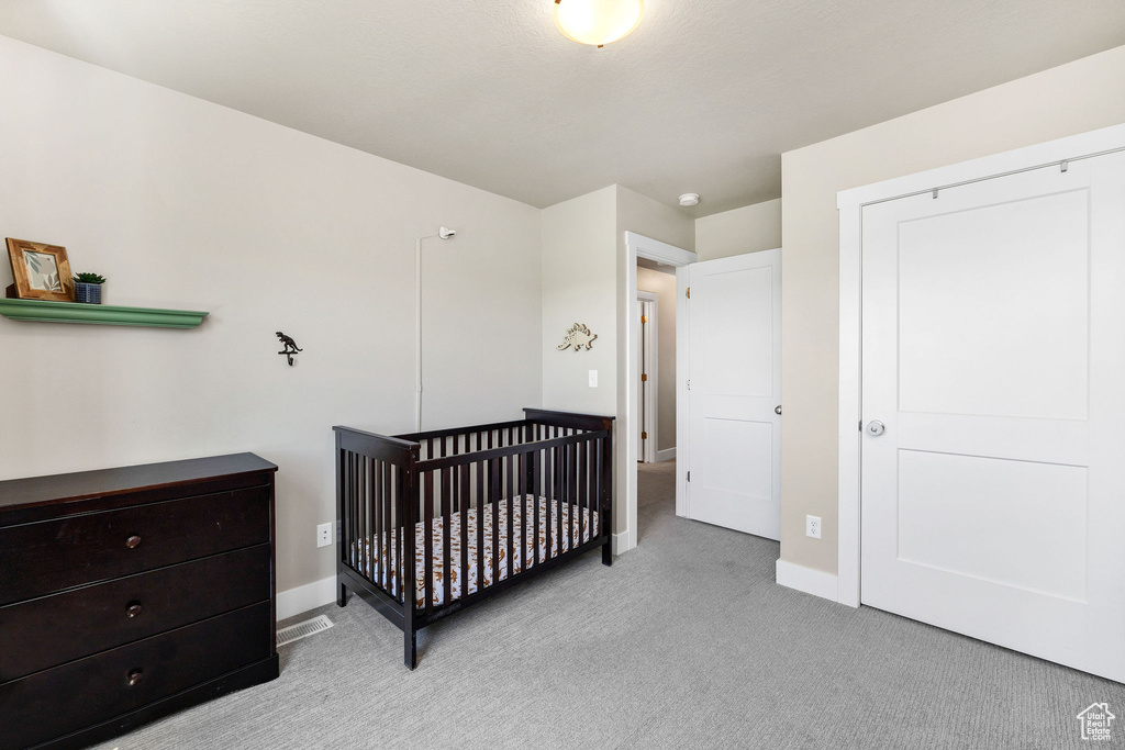 Carpeted bedroom with baseboards and a nursery area