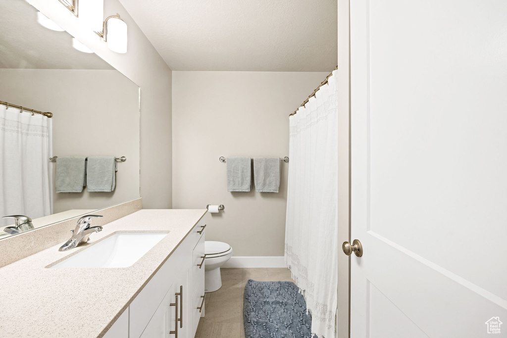 Bathroom with vanity, toilet, baseboards, and tile patterned flooring