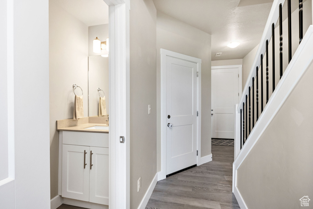 Corridor with a sink, wood finished floors, and baseboards