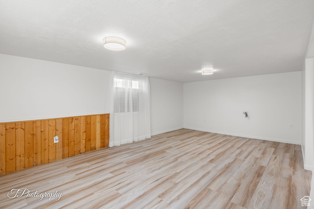 Unfurnished room with wood finished floors, wood walls, wainscoting, and baseboards