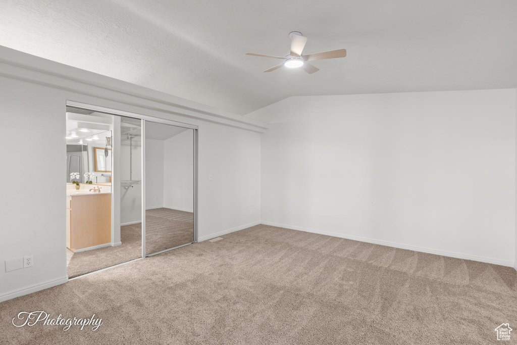 Unfurnished bedroom with carpet floors, lofted ceiling, a closet, baseboards, and ceiling fan