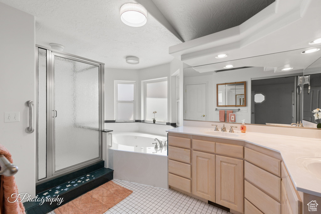 Bathroom featuring a bath, a shower stall, double vanity, a textured ceiling, and tile patterned flooring