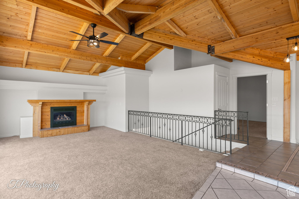 Unfurnished living room with wooden ceiling, a ceiling fan, beam ceiling, a fireplace, and tile patterned flooring