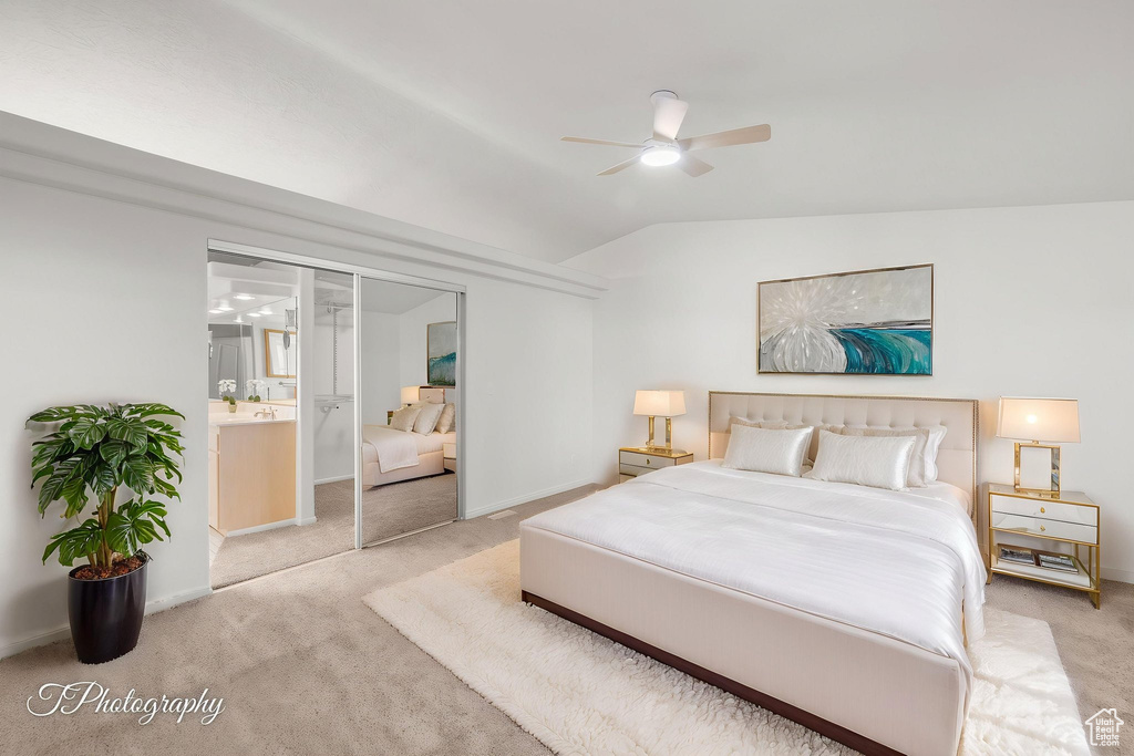 Bedroom featuring light carpet, vaulted ceiling, baseboards, and ensuite bath