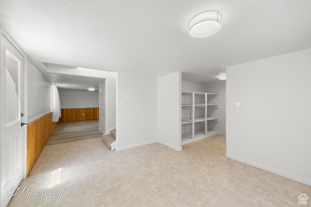 Empty room featuring wooden walls, a wainscoted wall, and stairway