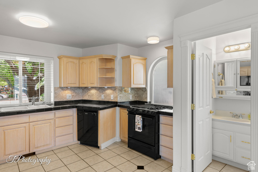 Kitchen with light brown cabinetry, black appliances, a sink, and tasteful backsplash