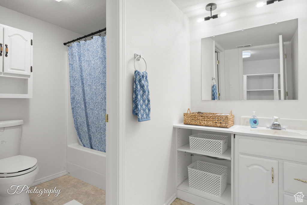 Bathroom with toilet, vanity, baseboards, shower / bath combination with curtain, and tile patterned flooring
