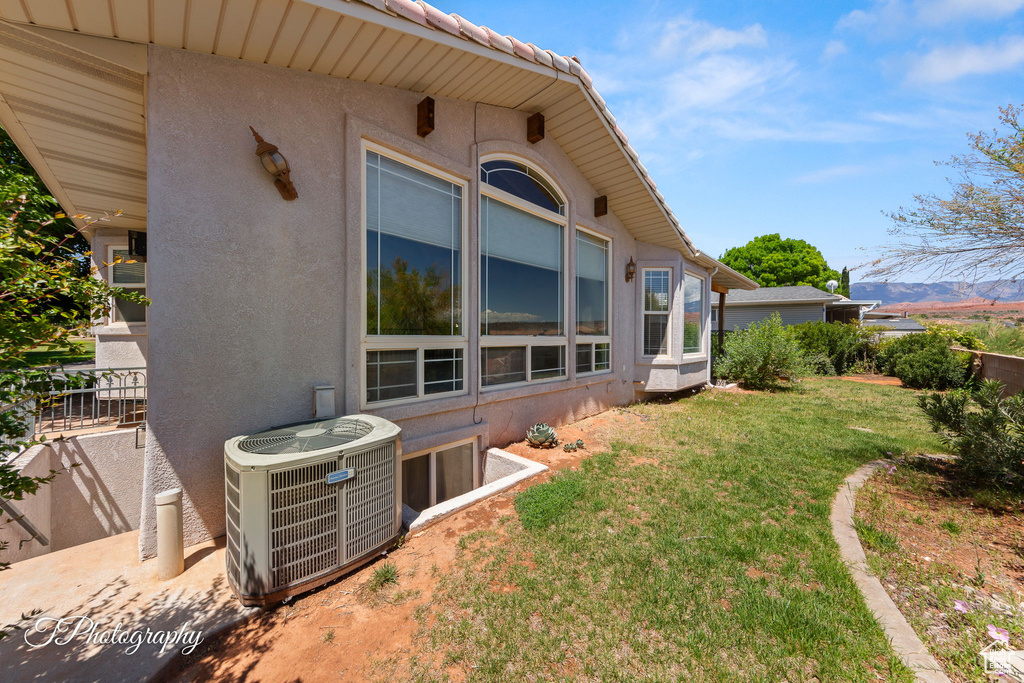 View of property exterior featuring cooling unit, a yard, and stucco siding