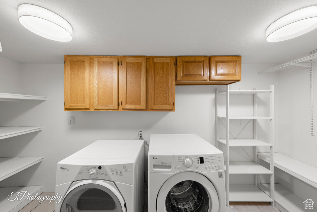 Washroom featuring cabinet space and washing machine and dryer