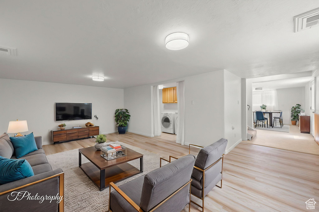 Living room with light wood-style flooring, washer / clothes dryer, and baseboards