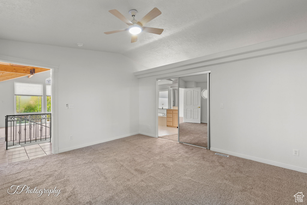 Unfurnished bedroom with carpet, lofted ceiling, baseboards, ensuite bath, and a ceiling fan