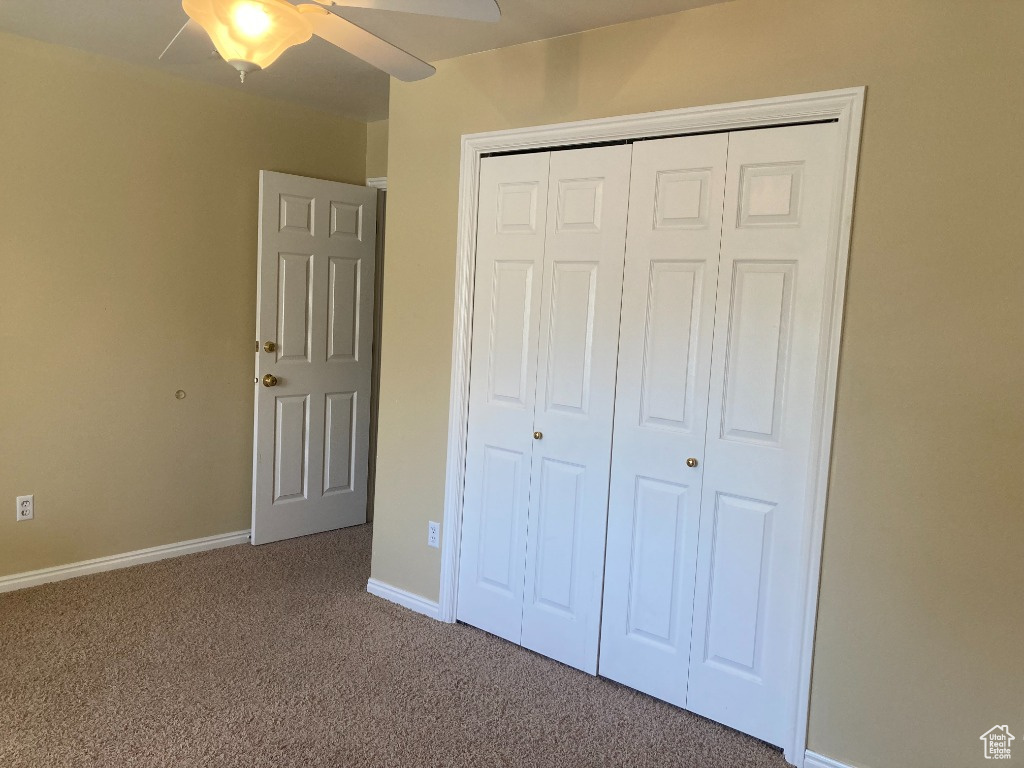 Unfurnished bedroom featuring carpet floors, a closet, baseboards, and a ceiling fan