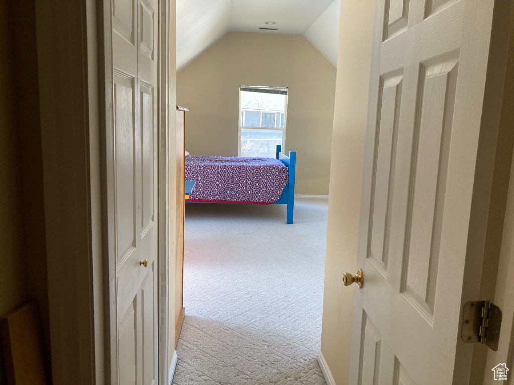 Carpeted bedroom with lofted ceiling and baseboards