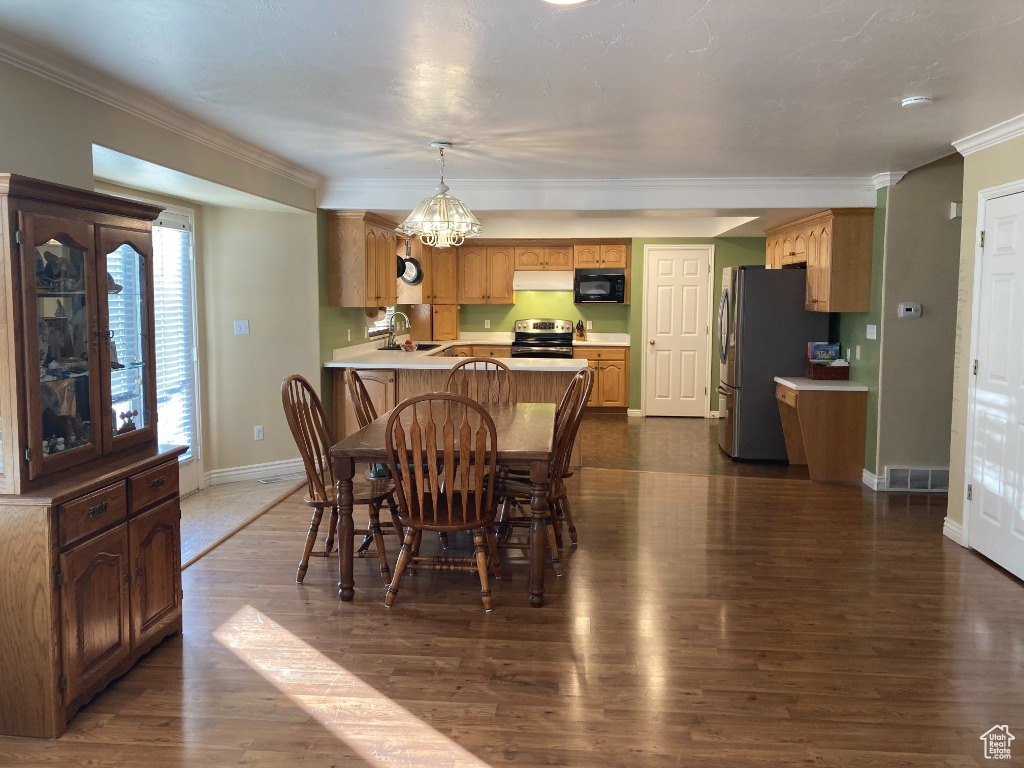 Dining room featuring baseboards, dark wood-type flooring, ornamental molding, and a chandelier