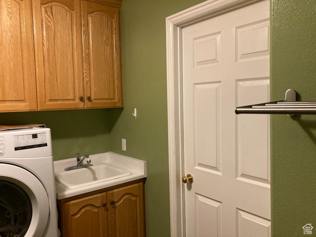 Clothes washing area featuring washer / clothes dryer and cabinet space