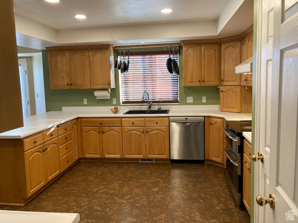 Kitchen with appliances with stainless steel finishes, a sink, dark flooring, light countertops, and recessed lighting