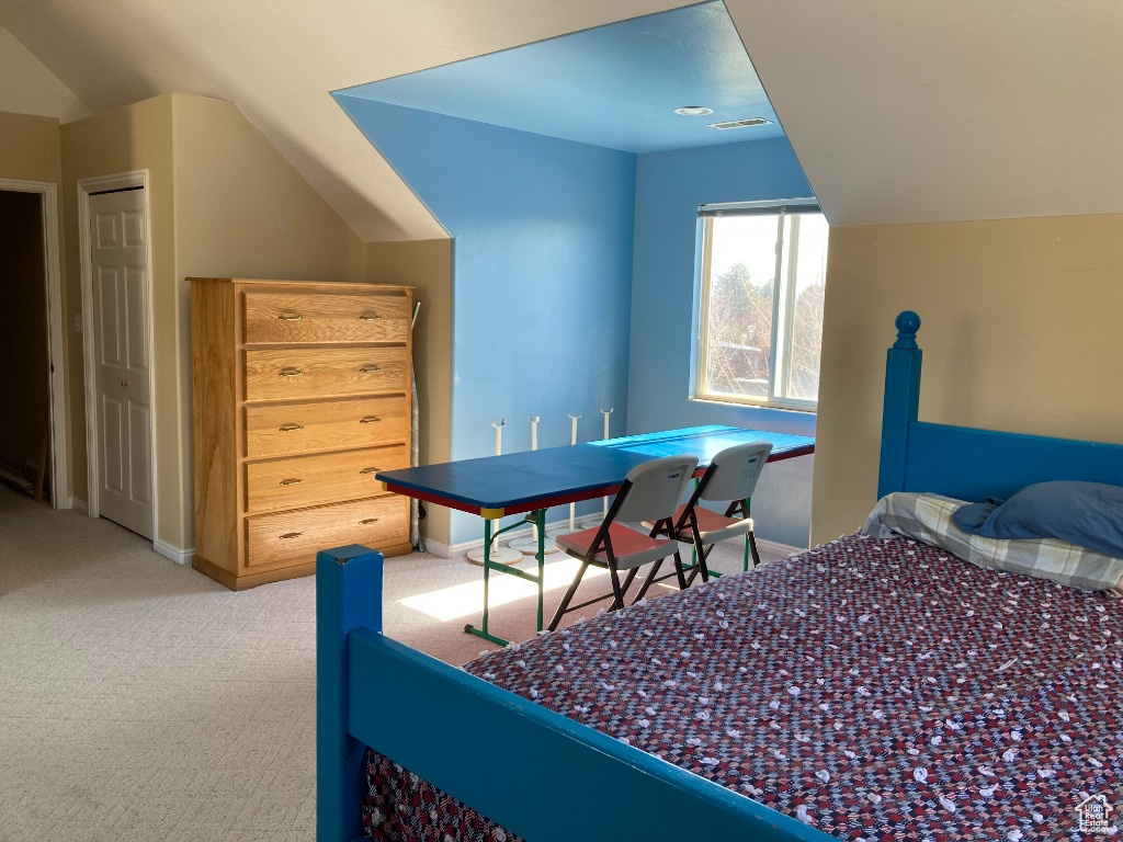 Carpeted bedroom with vaulted ceiling and baseboards