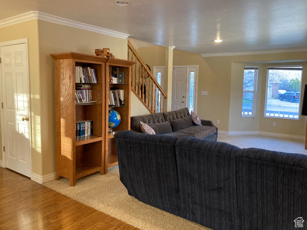 Living room featuring stairs, wood finished floors, baseboards, ornamental molding, and recessed lighting