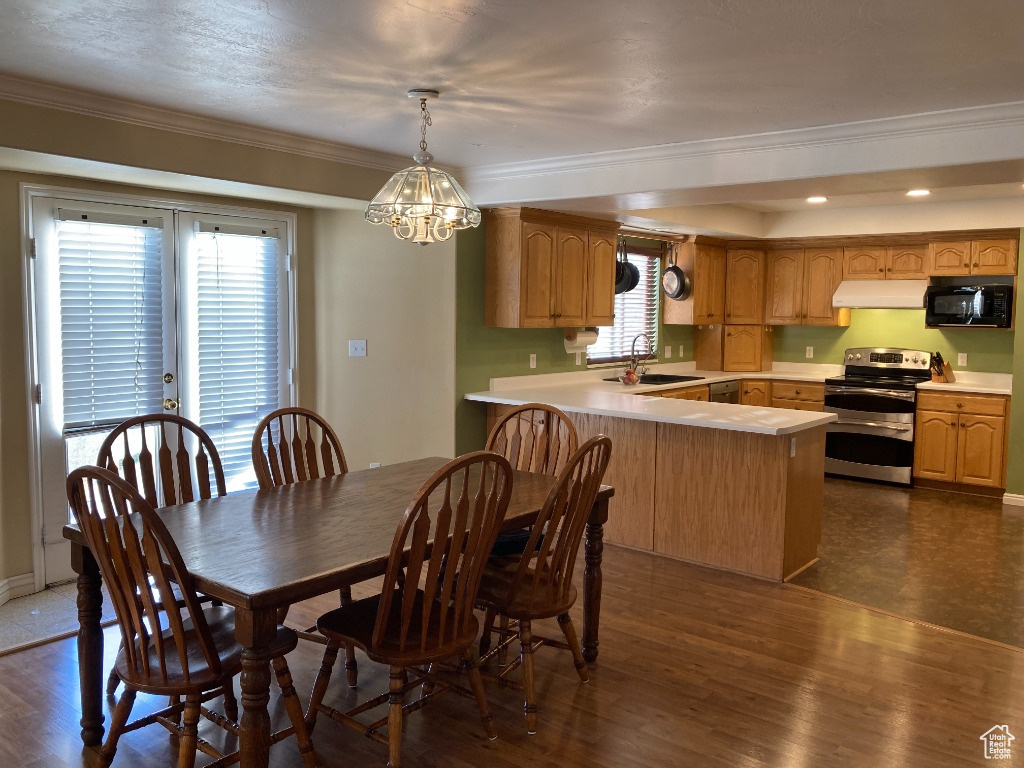 Dining area with a chandelier, dark wood-style flooring, ornamental molding, and recessed lighting