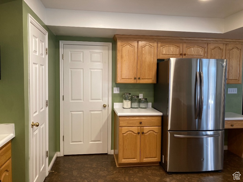Kitchen featuring freestanding refrigerator, light countertops, baseboards, and brown cabinetry