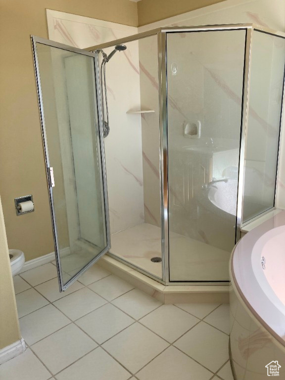 Bathroom with tile patterned floors, a shower stall, toilet, a bath, and baseboards