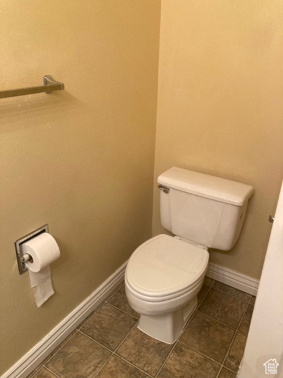 Bathroom featuring toilet, baseboards, and tile patterned flooring