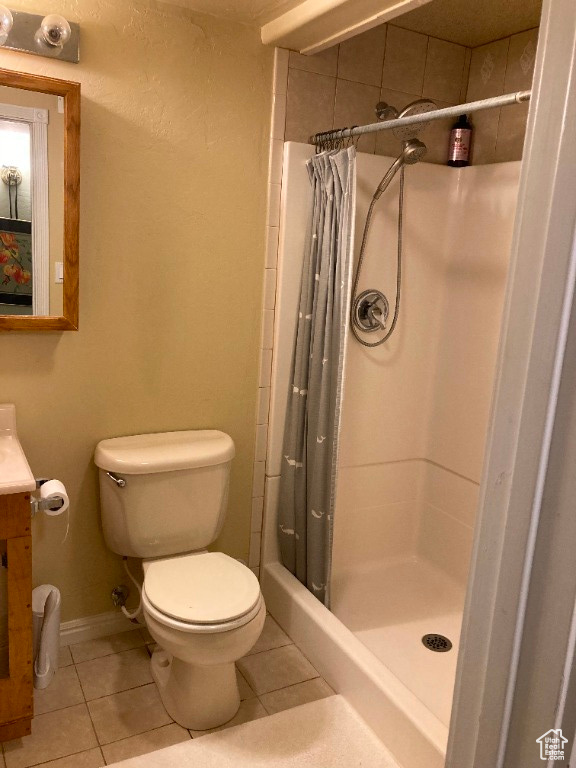 Bathroom featuring tile patterned flooring, toilet, a shower stall, baseboards, and vanity