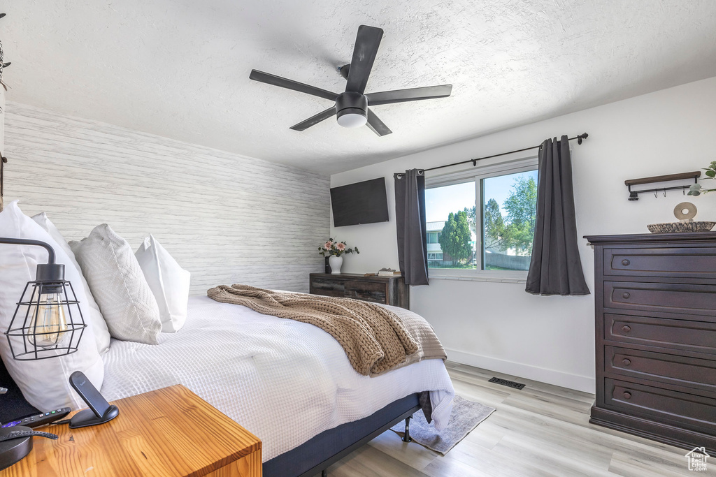 Bedroom with baseboards, light wood-style flooring, ceiling fan, and a textured ceiling