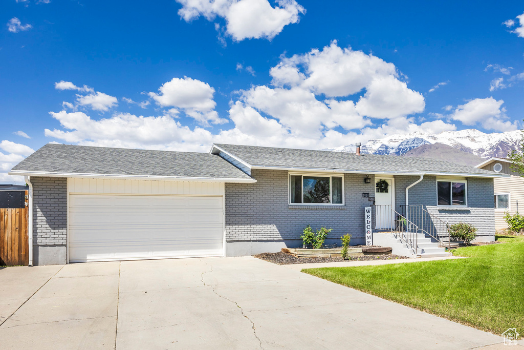 Ranch-style home with brick siding, a garage, concrete driveway, and a mountain view