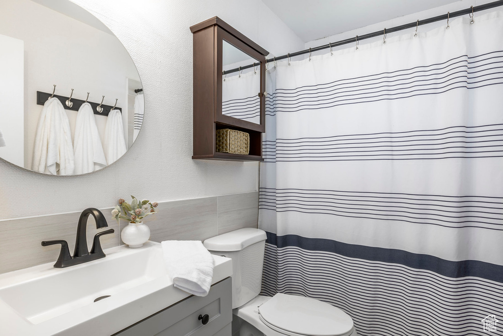 Bathroom with tile walls, toilet, and vanity