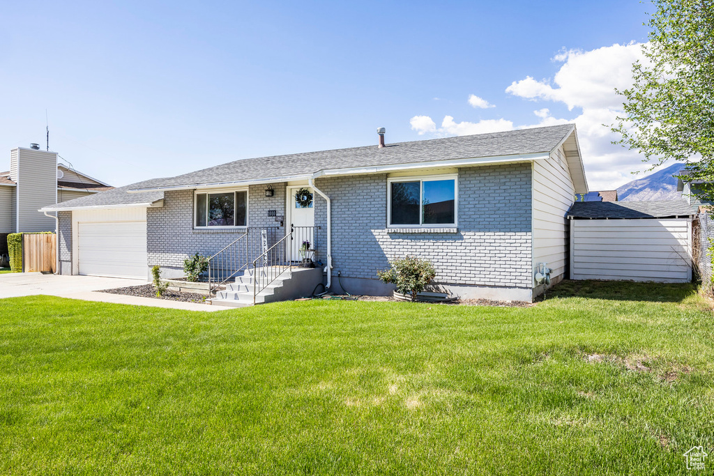 Ranch-style home featuring brick siding, a garage, concrete driveway, and a front lawn
