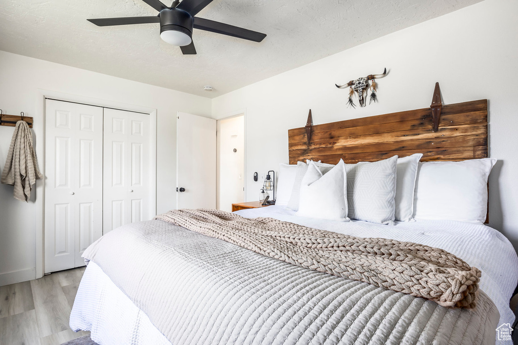 Bedroom featuring light wood-style flooring, a closet, a ceiling fan, and baseboards