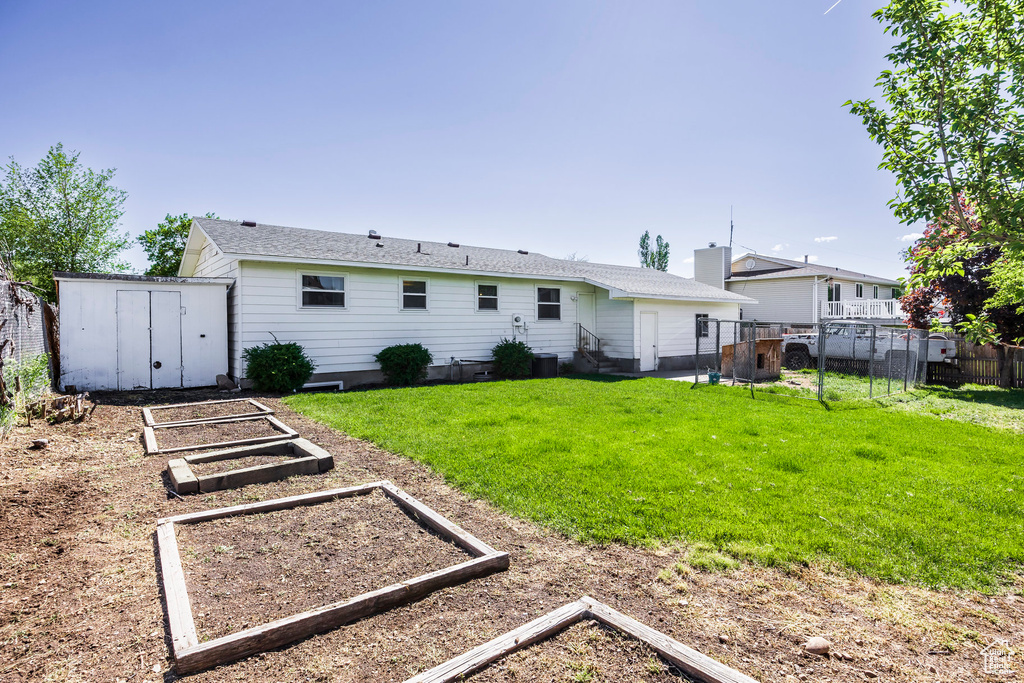 Rear view of house with a vegetable garden, a storage shed, an outdoor structure, and entry steps