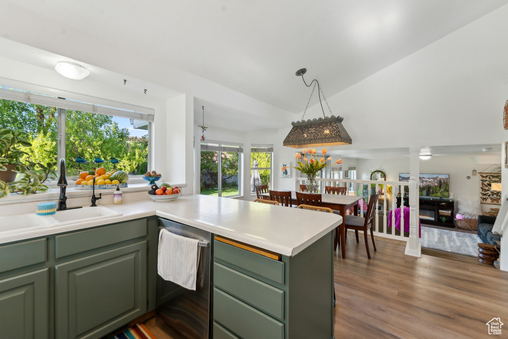 Kitchen with green cabinetry, a sink, dishwasher, a peninsula, and vaulted ceiling