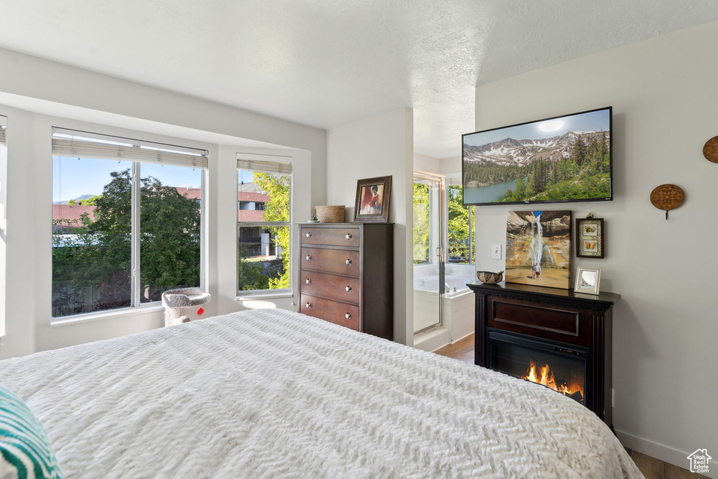 Bedroom with wood finished floors, a glass covered fireplace, and baseboards