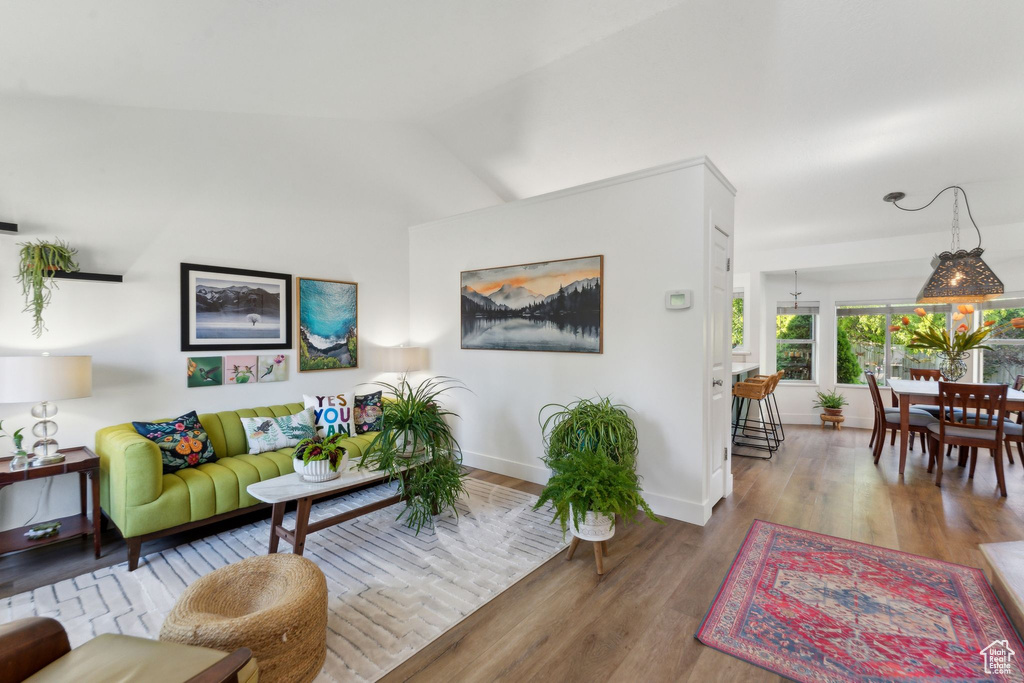 Living area with wood finished floors, baseboards, and vaulted ceiling
