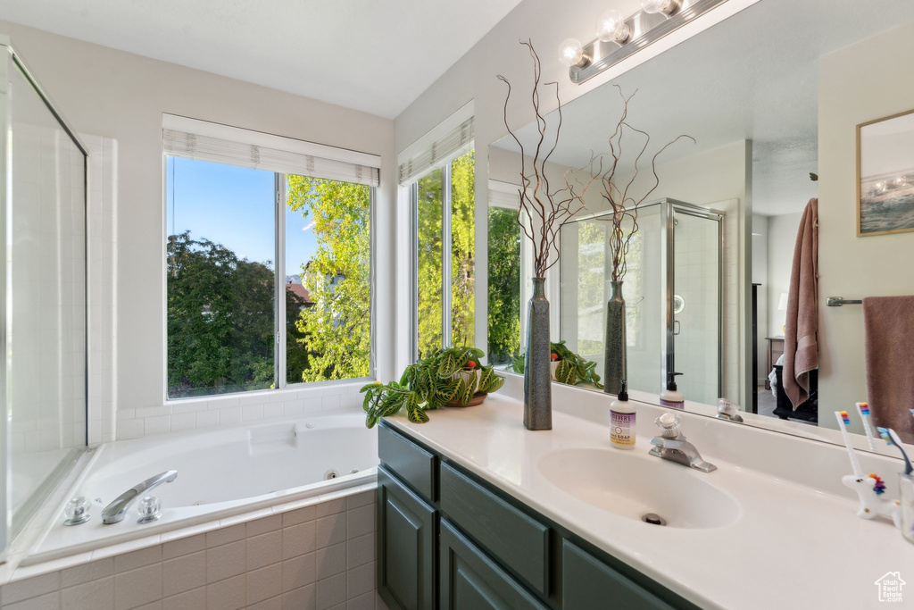 Bathroom with a shower stall, vanity, and a jetted tub