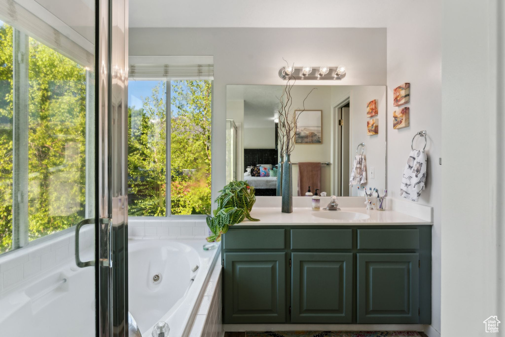 Full bath featuring vanity, a jetted tub, and connected bathroom