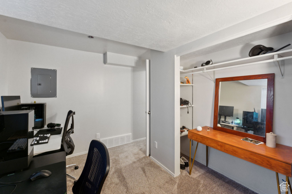 Carpeted office with electric panel, a textured ceiling, and baseboards