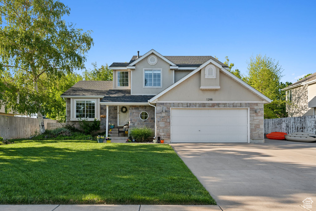 Traditional-style house featuring concrete driveway, stucco siding, stone siding, an attached garage, and roof with shingles