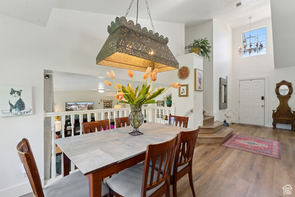 Dining area with a chandelier, wood finished floors, a high ceiling, and stairs