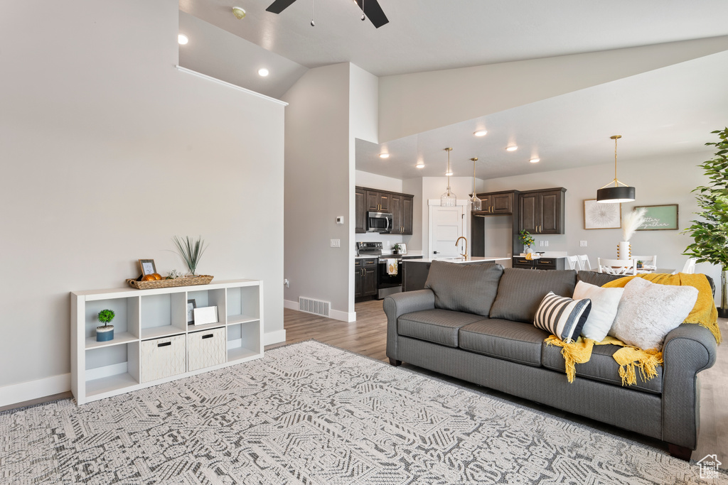 Living area featuring ceiling fan, light wood-type flooring, baseboards, recessed lighting, and high vaulted ceiling
