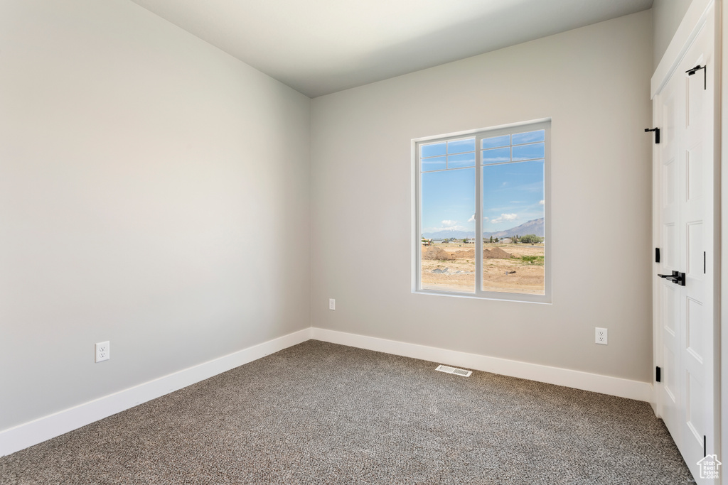 Unfurnished room with dark carpet and baseboards