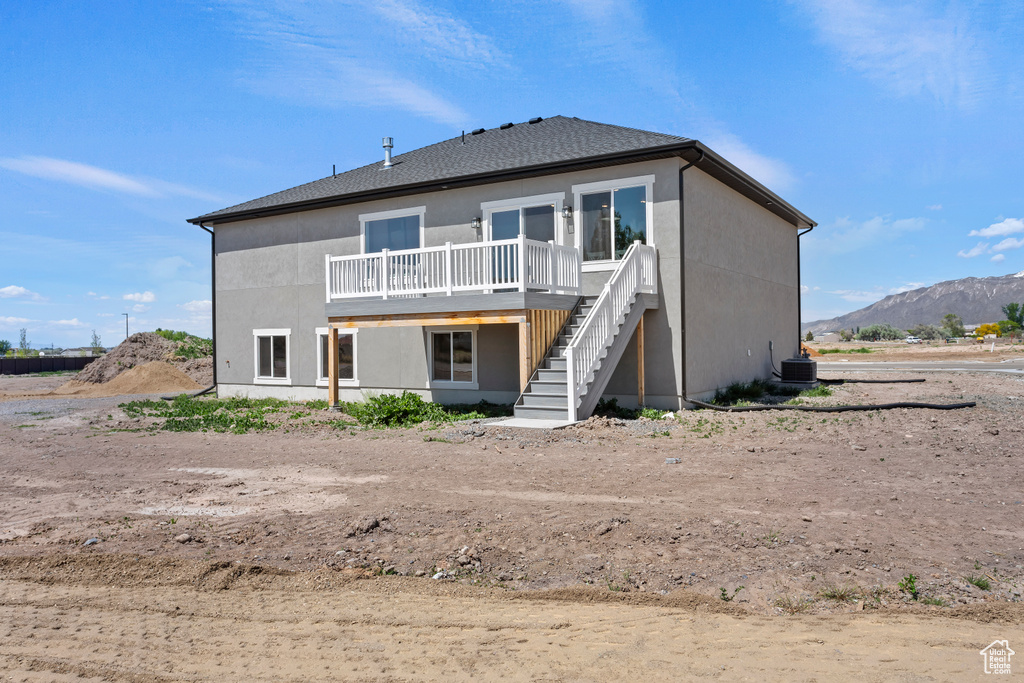 Rear view of house with stairway, a deck with mountain view, stucco siding, and central AC