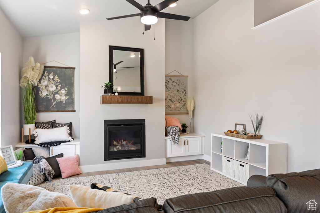 Living room with wood finished floors, ceiling fan, and a glass covered fireplace