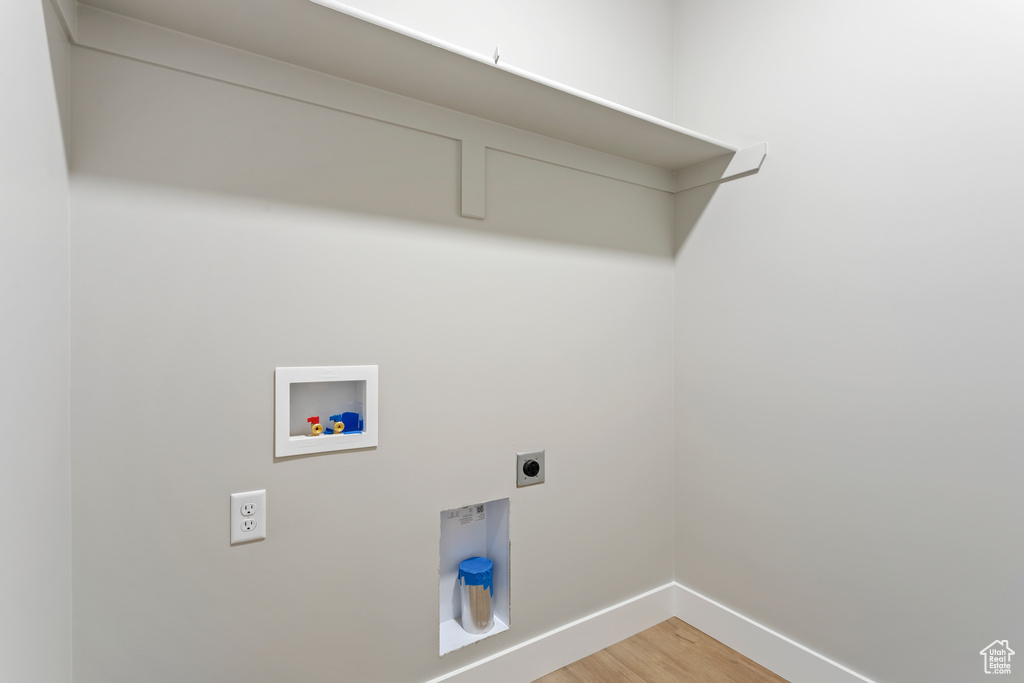 Washroom featuring hookup for a washing machine, hookup for an electric dryer, baseboards, and light wood-style flooring
