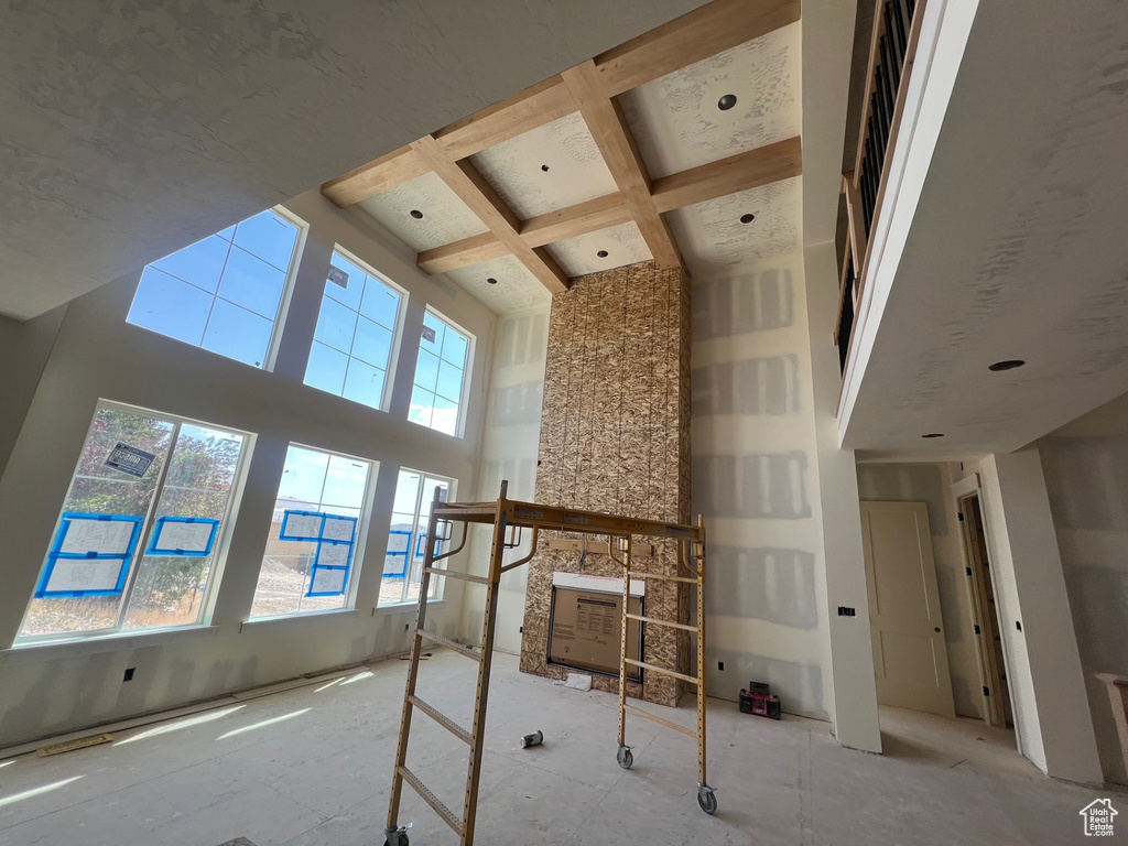 Unfurnished living room with a high ceiling, coffered ceiling, and beam ceiling