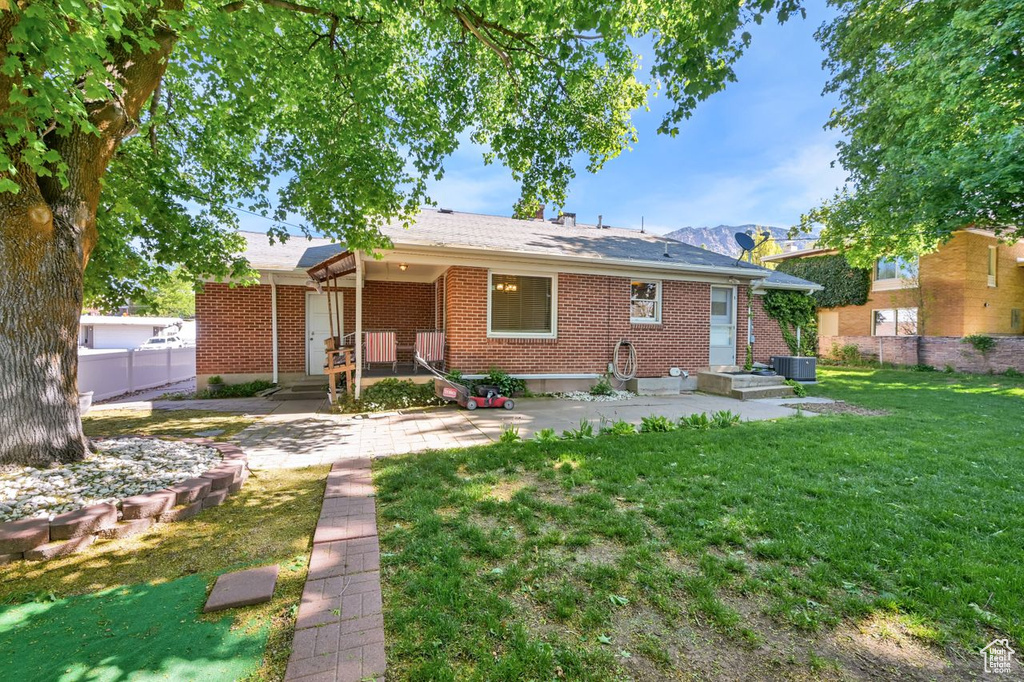 Rear view of property with central AC unit and brick siding