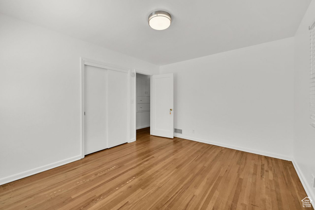 Unfurnished bedroom with light wood finished floors, a closet, and baseboards
