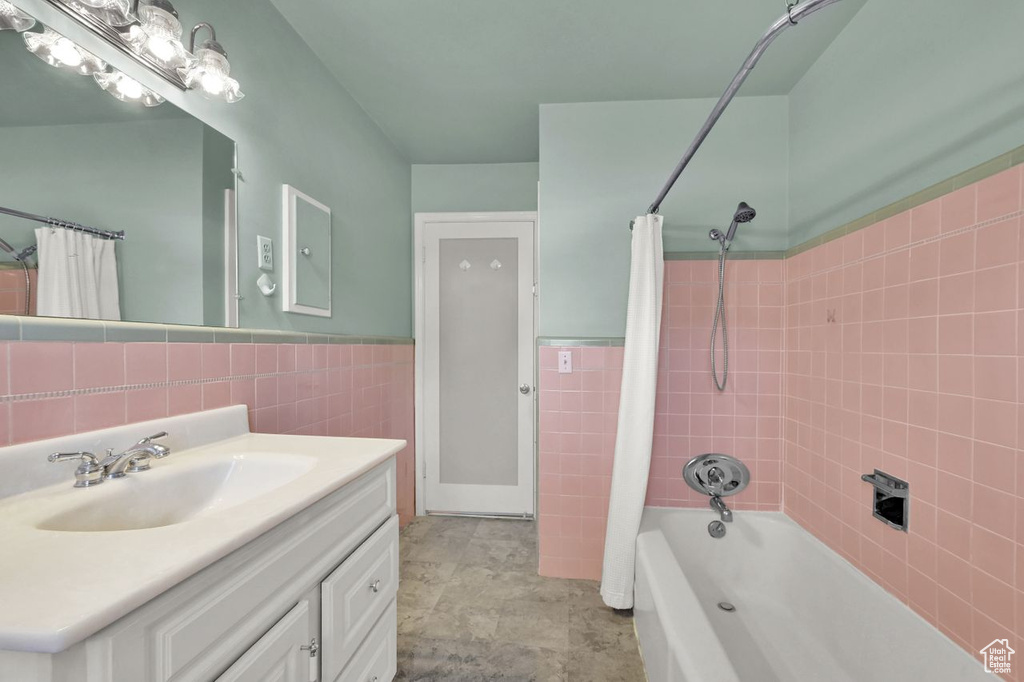 Bathroom featuring tile walls, shower / tub combo with curtain, vanity, and wainscoting